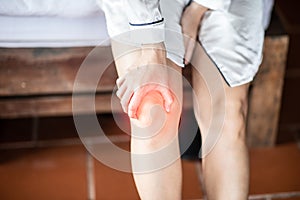 Woman have a kneecap pain sitting on bed in bedroom after wake up