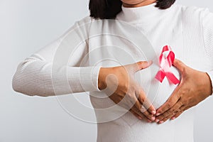 Woman she have pink breast cancer awareness ribbon on chest she hold breast by hand