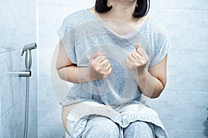 woman have problem with chronic constipation, bowel movement is painful sitting in toilet photo