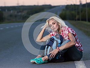 Woman with haversack sitting on the road photo