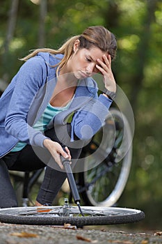 woman havign difficulty inflating bicycle tyre