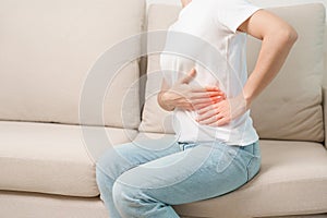 Woman having abdomen pain on the sofa at home. Liver cancer and Tumor, kidney cancer, Jaundice, Viral Hepatitis, Cirrhosis,
