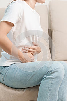 Una mujer con barriga dolor sobre el sofá sobre el. hígado cáncer a rinón cáncer ictericia inflamación del hígado cirrosis 