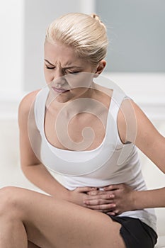 Woman having abdominal pain on sofa.