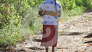 Woman having braid with machete walks along sunny road