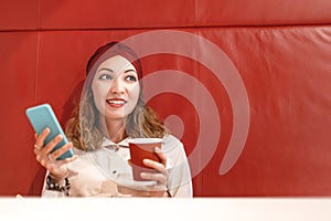 Woman having a break in coffee shop. Reading news in her smartphone