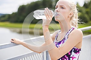 Woman having a break and drinks water after running