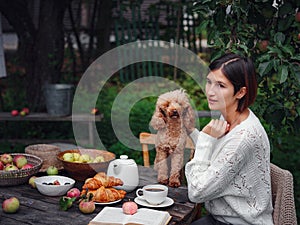 woman having breakfast in garden with her faithful pet poodle.