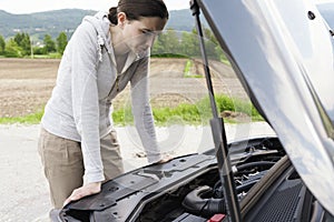 Woman having a car breakdown and staring at the engine