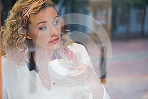 Woman having coffee seen through cafe window