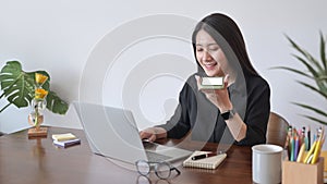 Woman having conversation on mobile phone and using computer laptop.