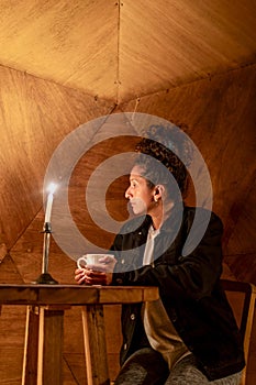 Woman having a cup of coffee sitting inside a dome tent.