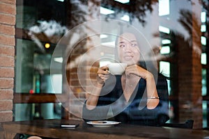 Woman having a cup of coffee by the window