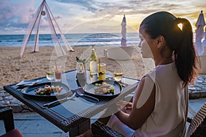 woman having Dinner during sunset on the beach in Phuket Thailand