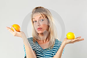 Woman having doubts between lemon and orange for beauty diet