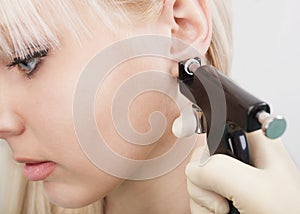 Woman having ear piercing process with special equipment