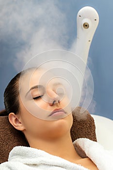 Woman having facial steam treatment in spa