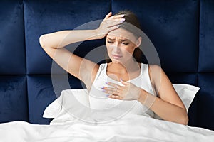 Woman Having Fever And Breathing Difficulty Sitting In Bed Indoors