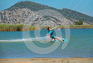 Woman having fun kitesurfing and dragging her hand along the surface of the sea.