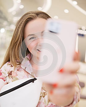 Woman having fun at the mall with her phone in her hands. She works remotely via her smartphone. She wears casual romantic summer