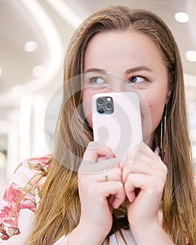 Woman having fun at the mall with her phone in her hands. She works remotely via her smartphone. She wears casual romantic summer