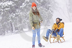 Woman having fun on winter vacation, sledging