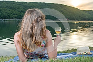 Woman having glass of wine by the lake