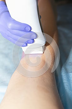 Woman having hair removal procedure on leg with wax depilatory in salon. Depilation concept