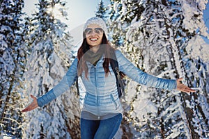 Woman having happy winter walk in snow covered woods