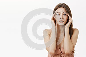 Woman having headache during periods feeling frustrated and concerned touching temples frowning from discomfort