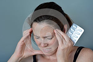 Woman having headache taking pills photo