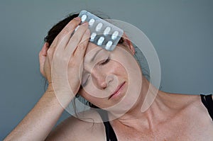 Woman having headache taking pills photo