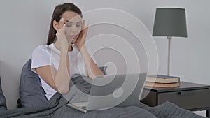 Woman having Headache while Working on Laptop in Bed
