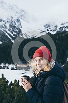 Žena s horúcim nápojom z termohrnčeka s výhľadom na zasnežené štíty Vysokých Tatier
