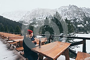 Woman having a hot drink from thermo cup overlooking snowcapped High Tatra mountains peaks