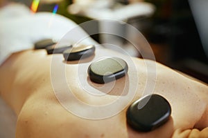 Woman having hot stone massage and laying on massage table
