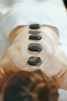 Woman having hot stone massage and laying on massage table