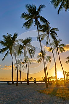 A woman having a jog along Waikiki Beach with an amazing orange sunset.