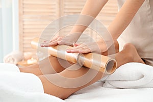 Woman having massage with bamboo stick in wellness center