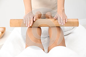 Woman having massage with bamboo stick in wellness center