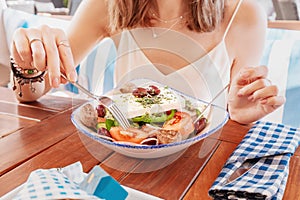 Woman having meal with greek salad Horiatiki in restaurant. Greece cuisine concept