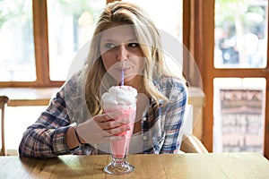 Woman having milkshake at table in coffee shop