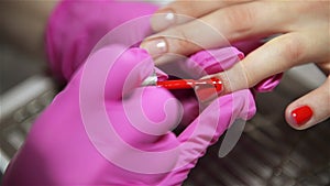 Woman having a nail manicure in a beauty salon with a close up view of a beautician applying varnish with an applicator