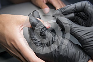 Woman having a nail manicure in a beauty salon with a closeup view of a beautician applying varnish with an applicator.