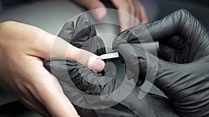 Woman having a nail manicure in a beauty salon with a closeup view of a beautician applying varnish with an applicator.