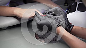 Woman having a nail manicure in a beauty salon with a closeup view of a beautician applying varnish with an applicator