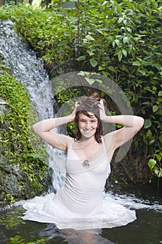 Woman having a natural spa bath in a waterfall