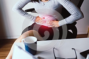 Woman having painful stomach ache during working from home,Female suffering from abdominal pain,Period cramps,Hands squeezing bell