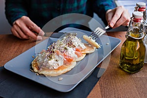 Woman having a pancake with salmon and sourcream in a restaurant. Tasty homemade breakfast
