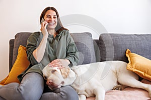 Woman having phone conversation and cuddling her dog